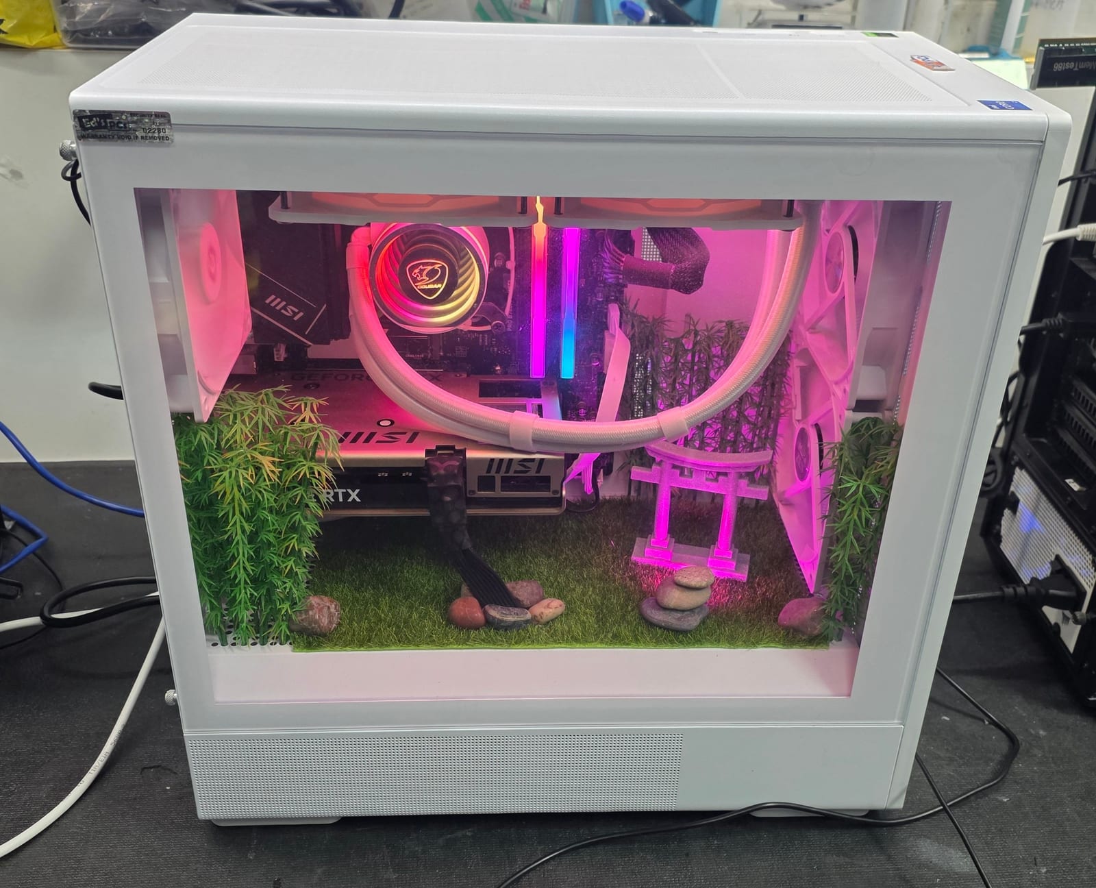The same white case lit pink, showing the full front glass and the garden below