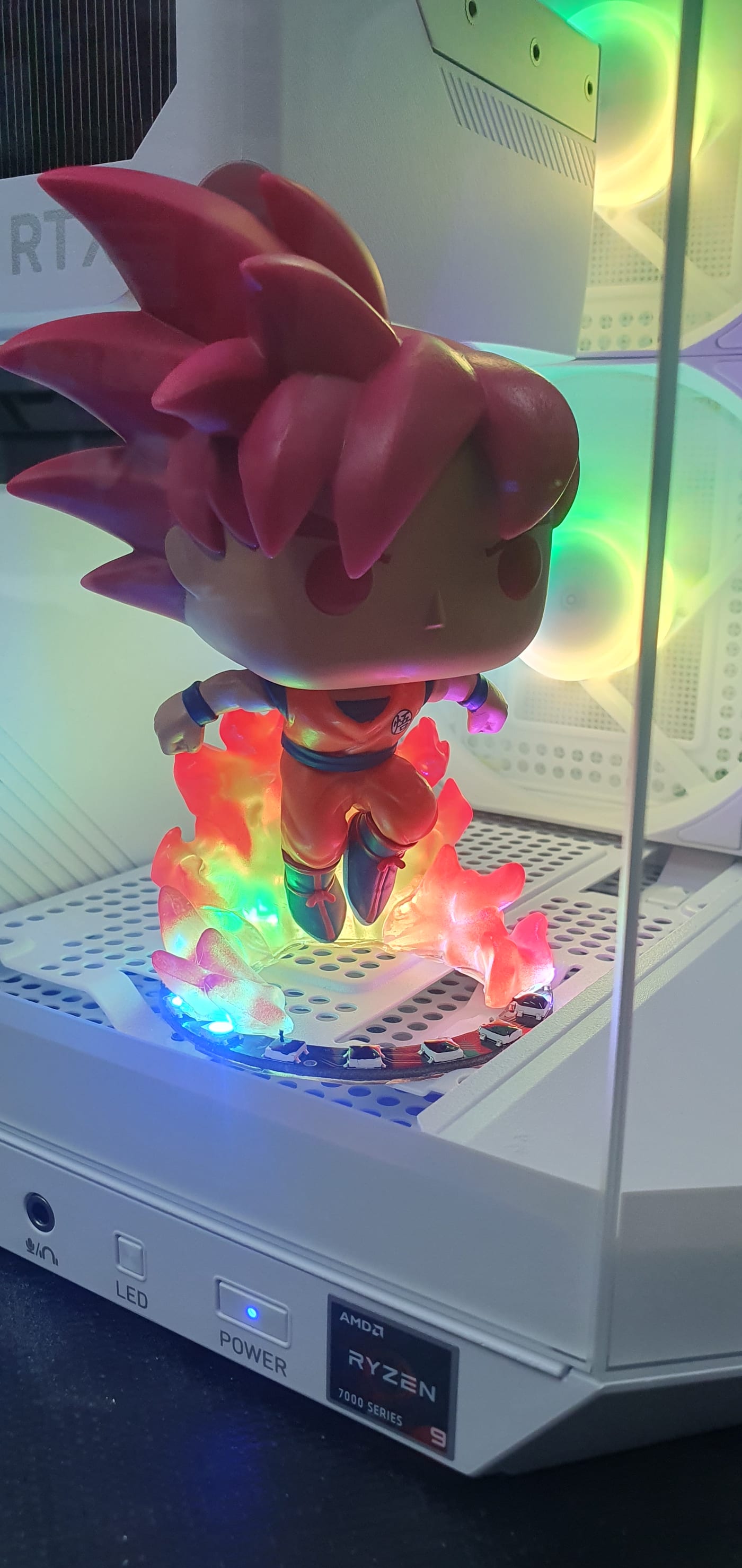 Close view of a lit figure standing on an illuminated flame-effect base inside the lower chamber of a white PC case