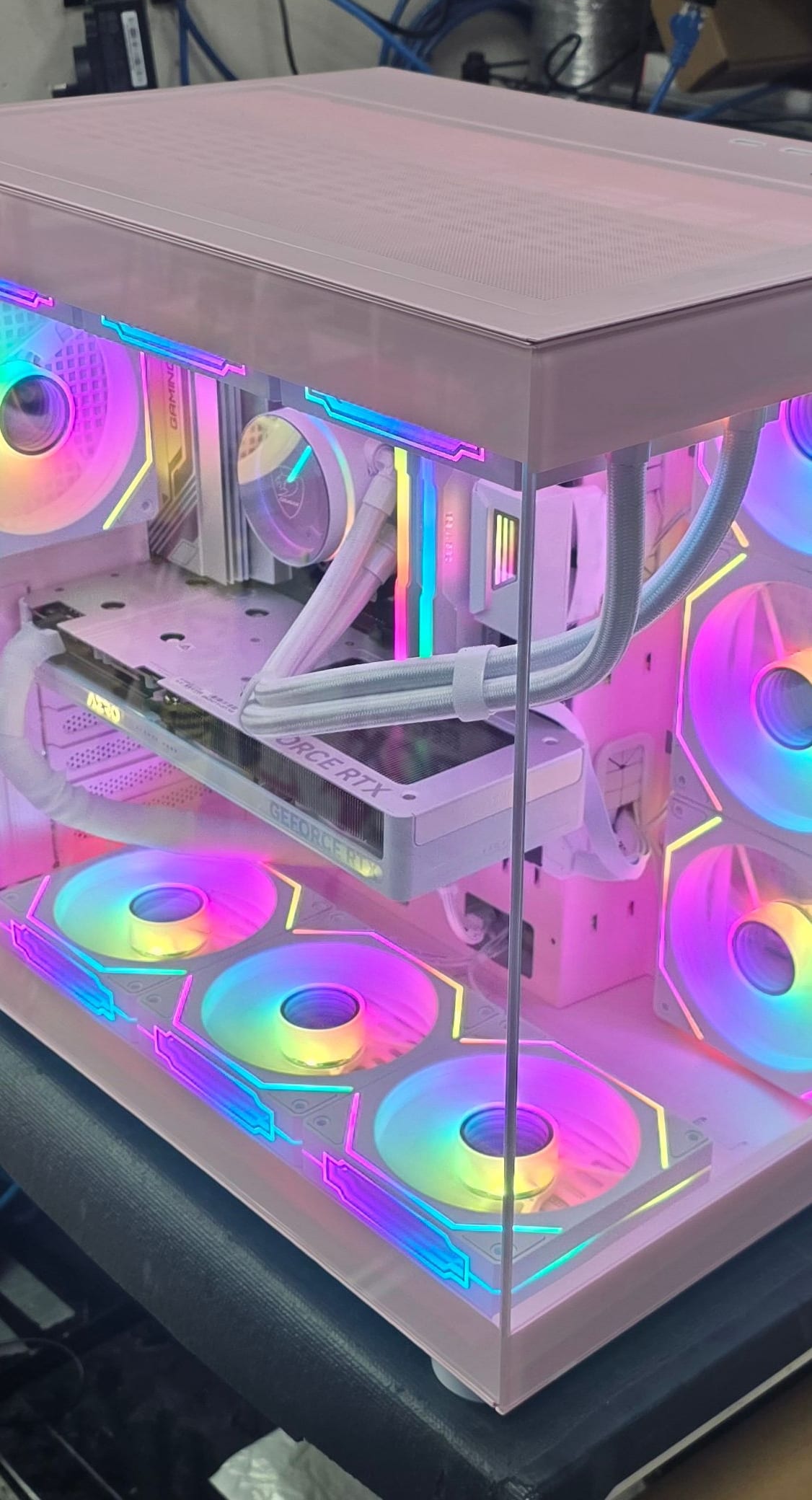 The pink case from above, looking down through the top glass at the fans and white-sleeved loop
