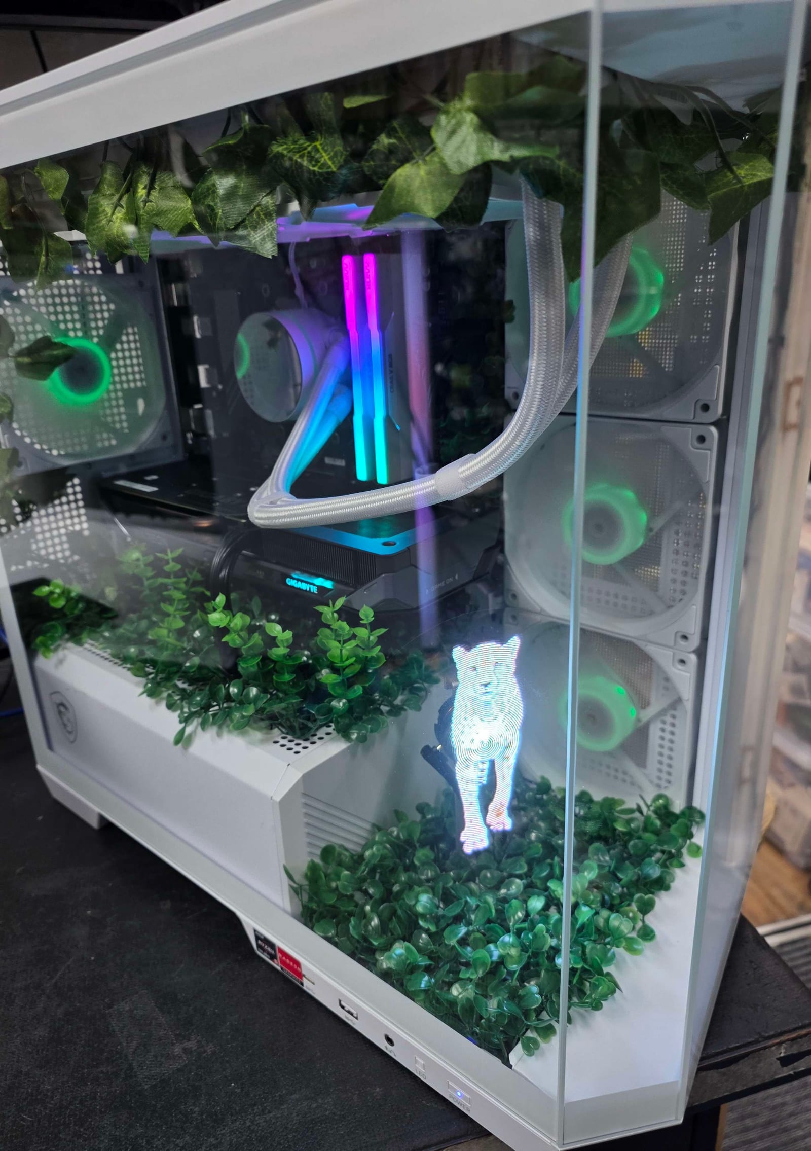 A white PC case planted with moss and ivy, showing a holographic display of a walking leopard among the foliage, lit green