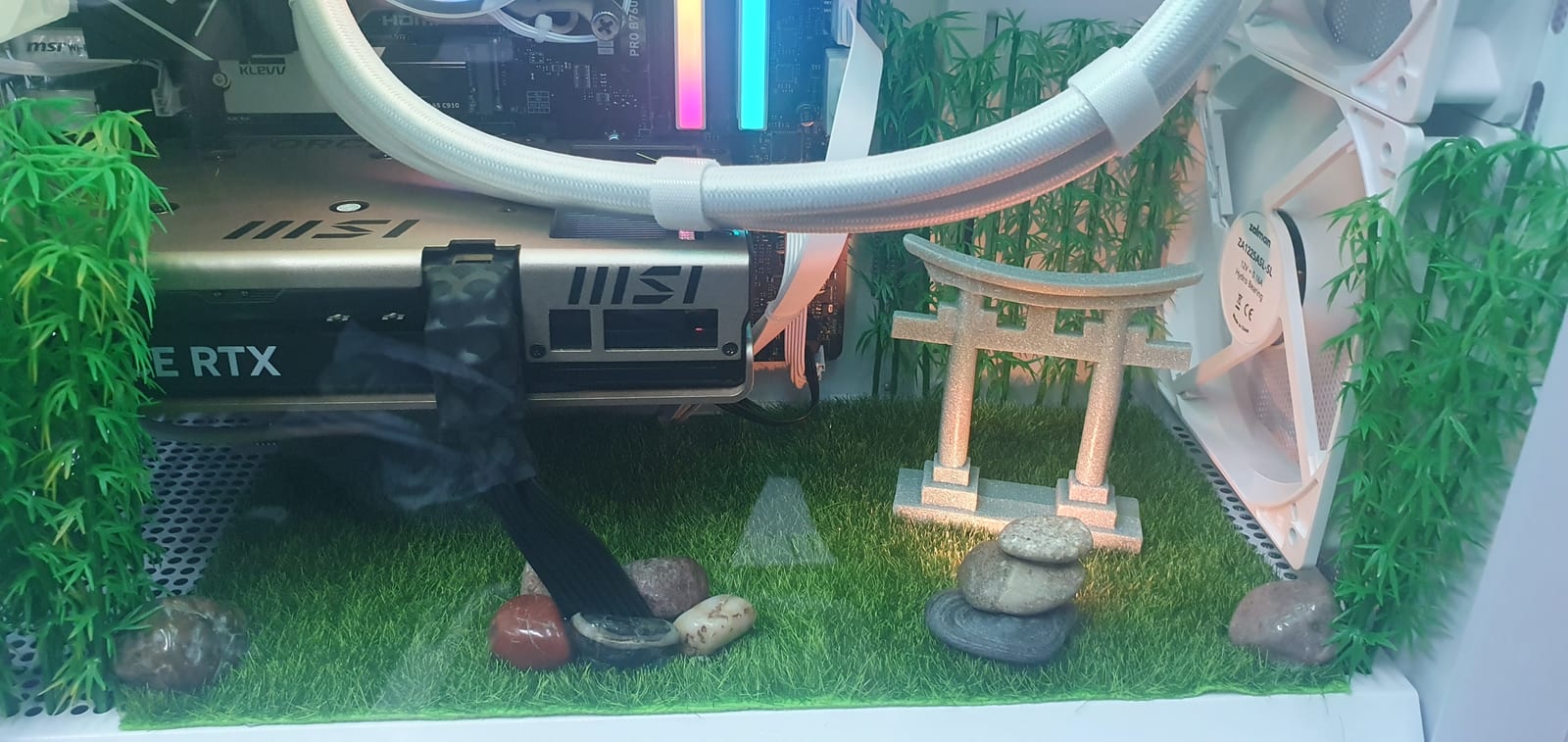A miniature torii gate and stacked river stones on artificial turf, built into the floor of a PC case