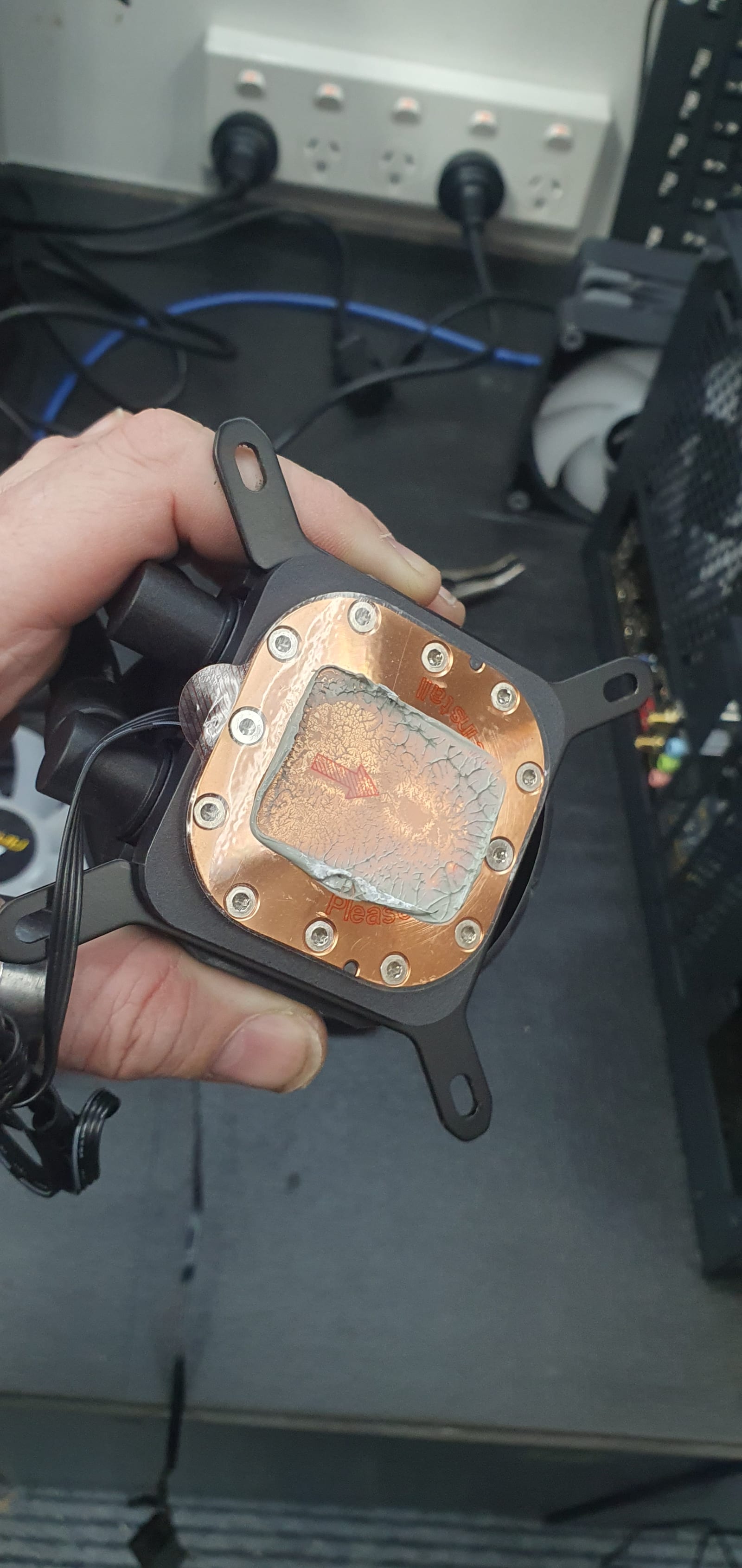 A CPU water block held in hand, its thermal paste dried, cracked and crazed across the contact surface from years without a repaste