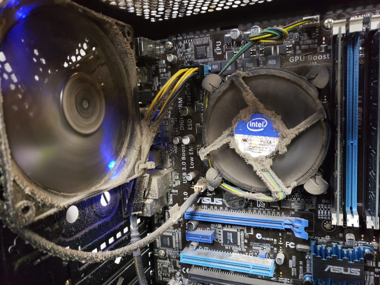 A CPU heatsink fan and surrounding motherboard completely caked in thick grey dust, wiring barely visible underneath the buildup