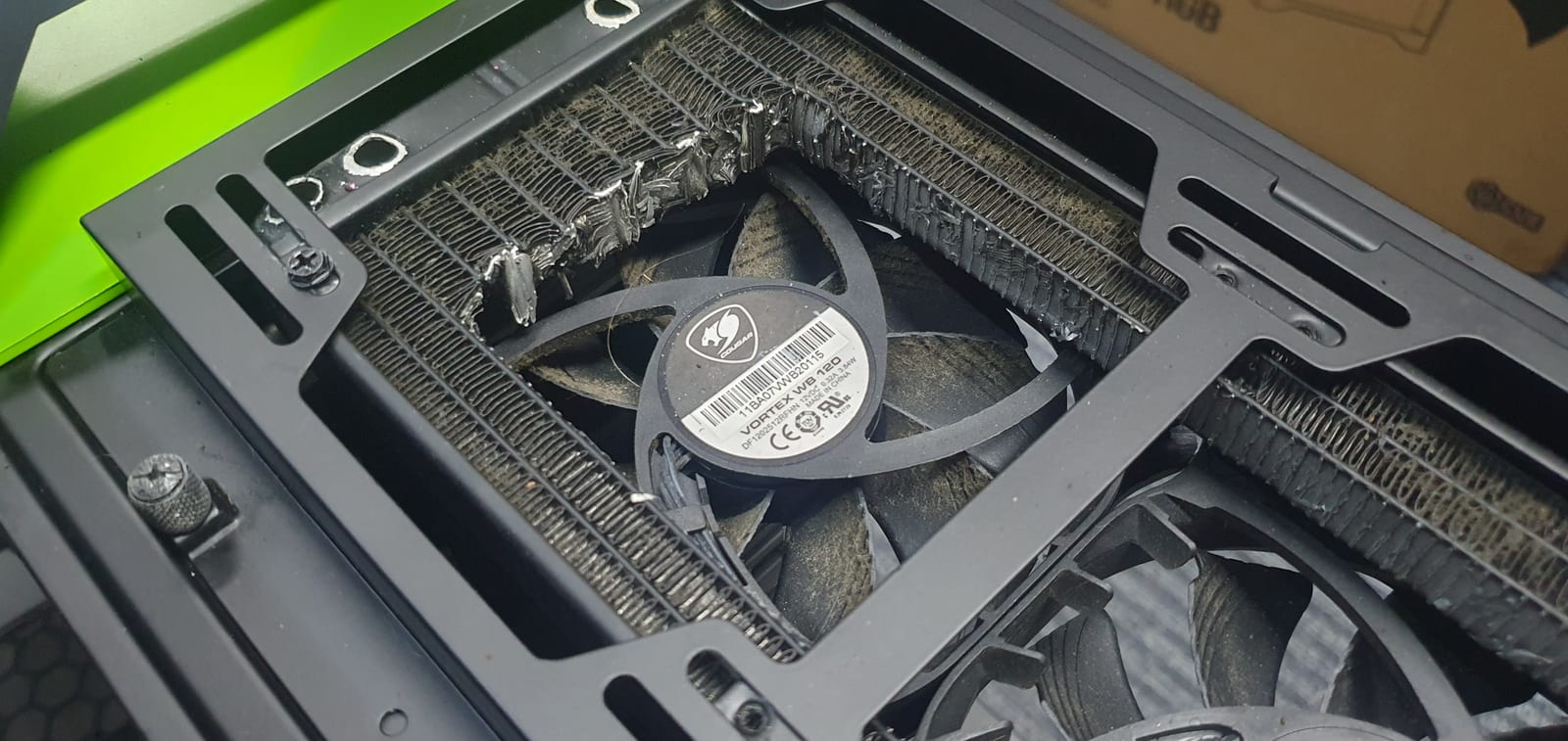 A case radiator and fan felted solid with matted grey lint and dust, almost no airflow gap remaining between the fins