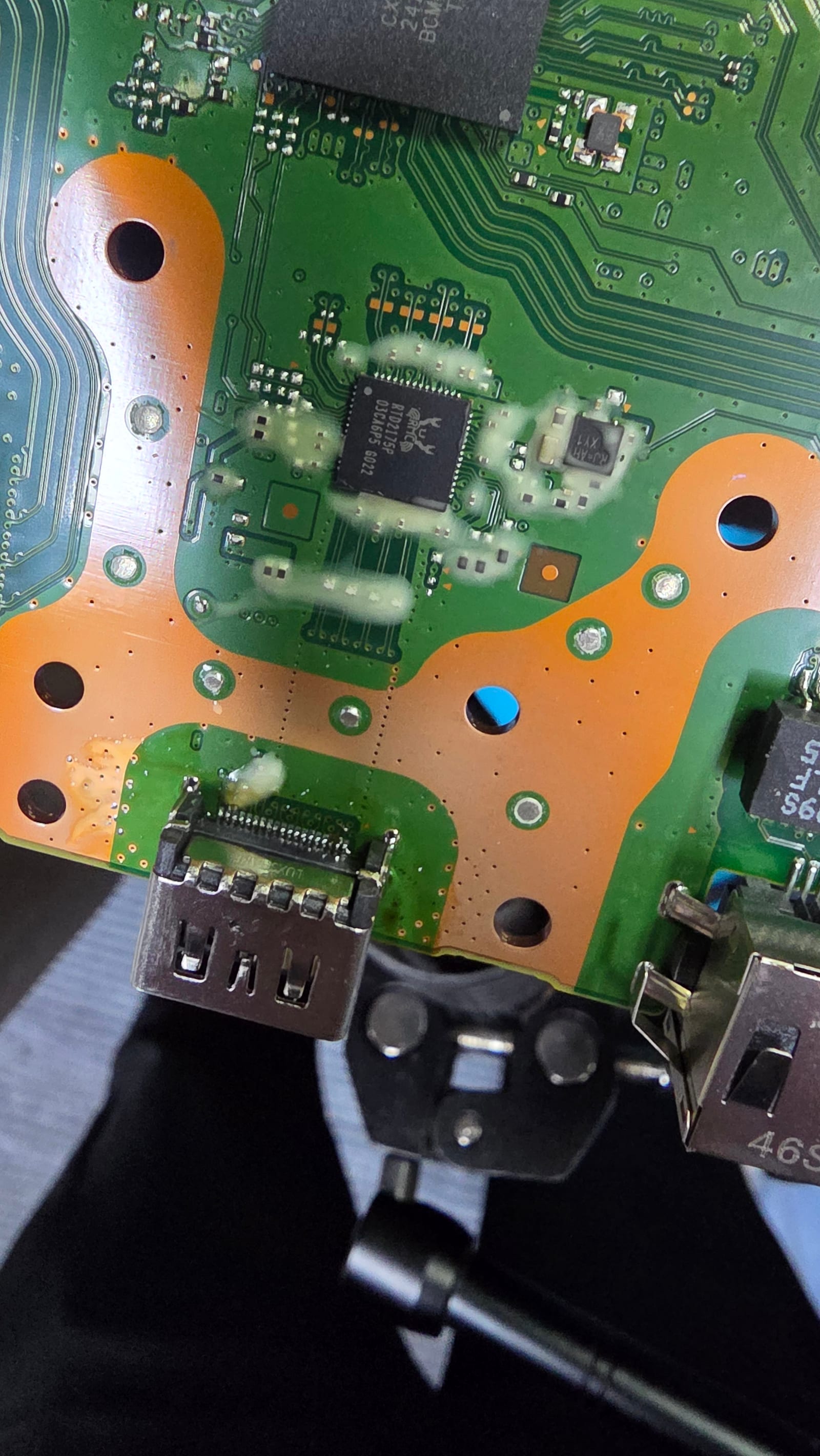 A new HDMI port freshly soldered onto a PS5 mainboard, still mounted in the board holder on the rework bench