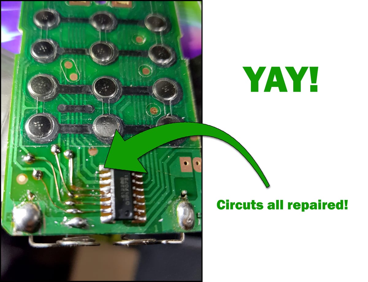 A remote control circuit board repaired with fine jumper wires soldered in to rebuild every broken track to the chip