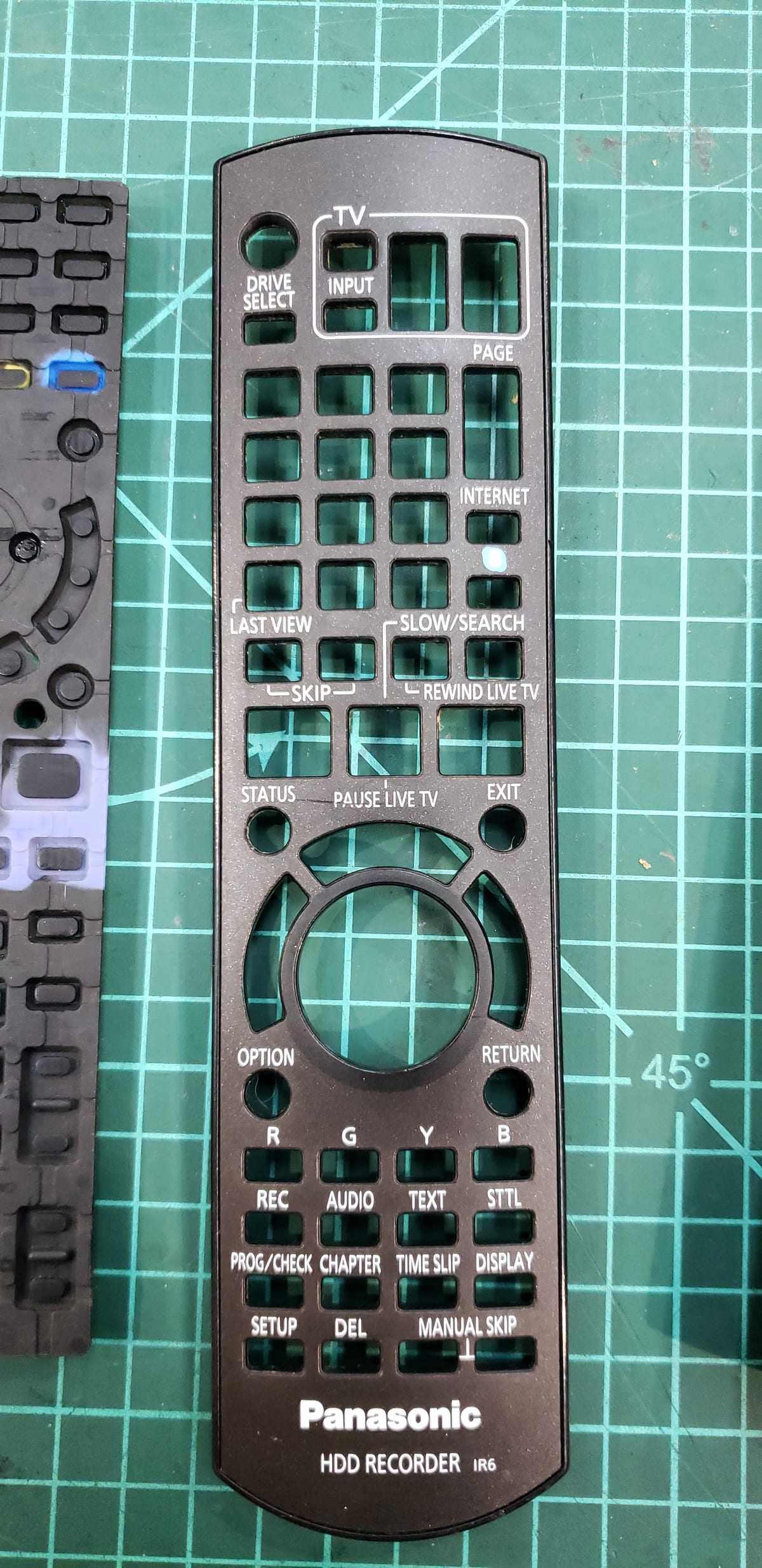 The same Panasonic remote's outer shell, stripped down and cleaned spotless on the same cutting mat